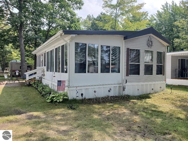 view of side of property featuring a lawn and a sunroom