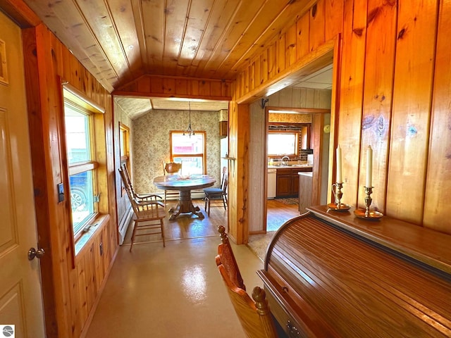 corridor featuring concrete flooring, wooden ceiling, vaulted ceiling, and wood walls