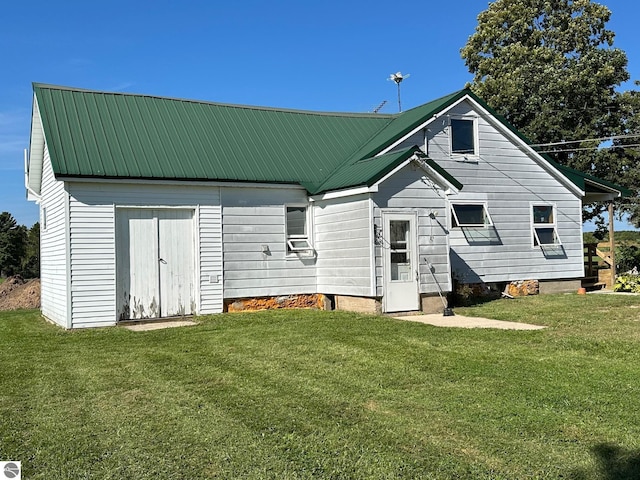 back of property featuring metal roof, a lawn, and an outdoor structure