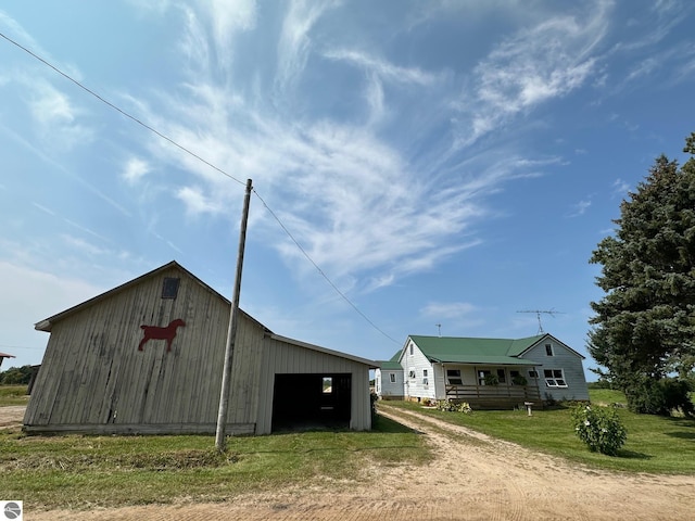 view of pole building with a lawn and dirt driveway