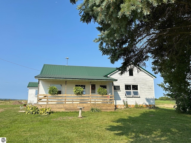 view of front of property featuring covered porch, metal roof, and a front lawn