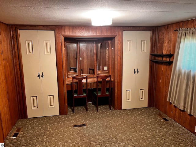 office space with carpet, wood walls, and a textured ceiling