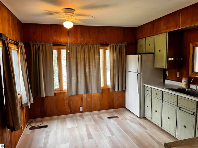 kitchen featuring sink, wooden walls, light hardwood / wood-style floors, and ceiling fan