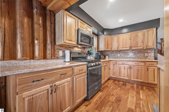 kitchen with light wood-type flooring, light stone counters, tasteful backsplash, stainless steel appliances, and light brown cabinets