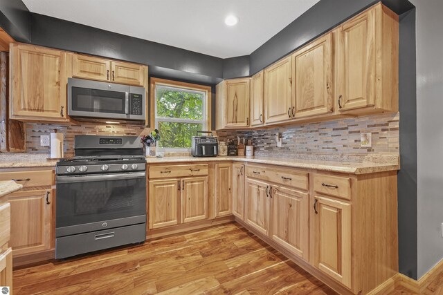 7504 W Dakota Trl, Lake City, MI 49663 - kitchen featuring light wood-style flooring, decorative backsplash, light brown cabinetry, and appliances with stainless steel finishes