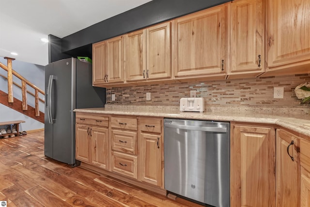 kitchen featuring light stone counters, appliances with stainless steel finishes, dark hardwood / wood-style flooring, and tasteful backsplash