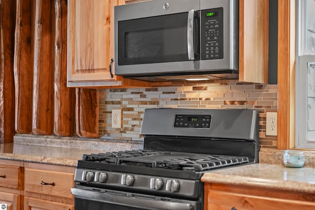 kitchen featuring light stone countertops, appliances with stainless steel finishes, and tasteful backsplash