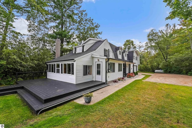 rear view of house featuring a wooden deck and a yard