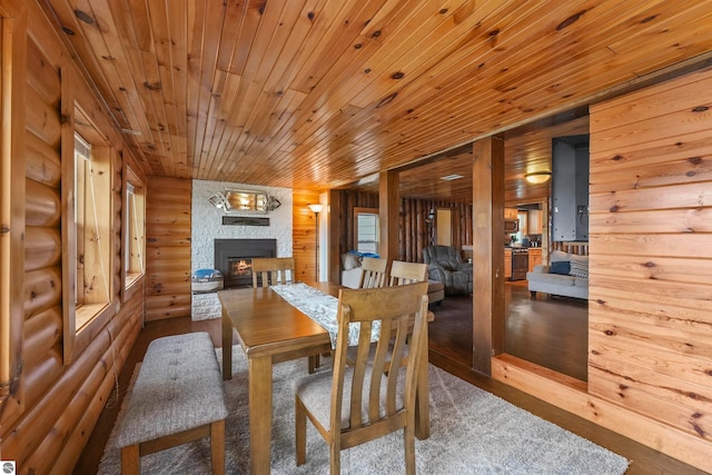 dining area with a stone fireplace, hardwood / wood-style flooring, wood walls, and wooden ceiling