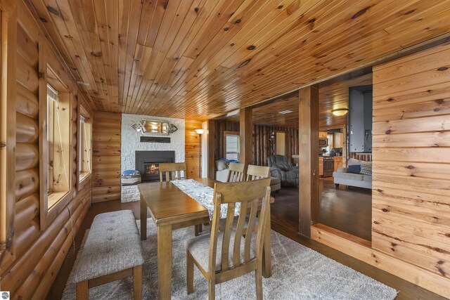 7504 W Dakota Trl, Lake City, MI 49663 - dining area featuring wood ceiling, log walls, wood finished floors, and a stone fireplace