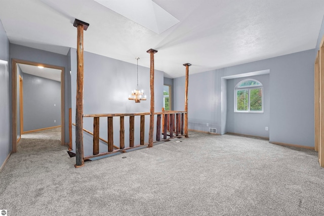 spare room featuring carpet flooring, an inviting chandelier, and a skylight