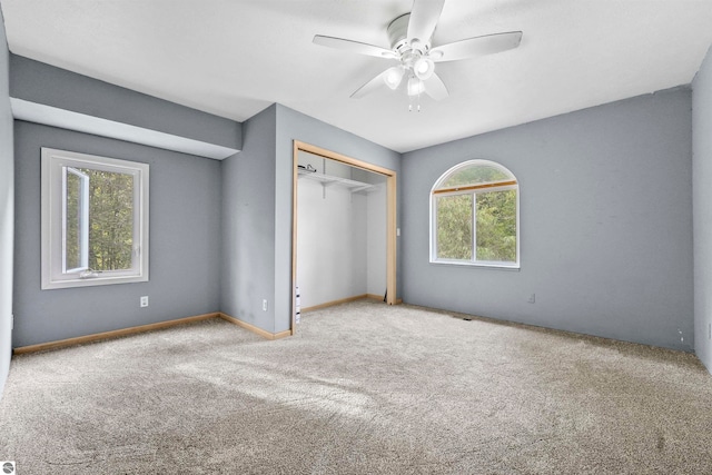 unfurnished bedroom featuring multiple windows, ceiling fan, light colored carpet, and a closet