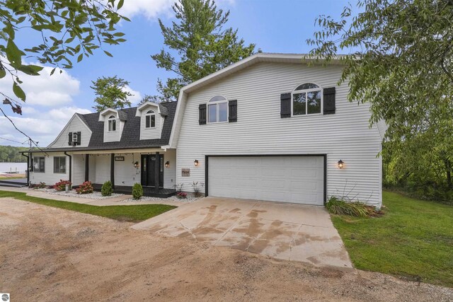 7504 W Dakota Trl, Lake City, MI 49663 - view of front of home featuring a porch, a front lawn, an attached garage, a shingled roof, and concrete driveway