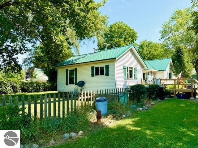 back of property featuring metal roof, a yard, fence, and a wooden deck