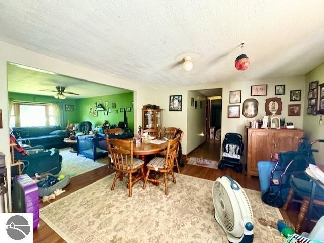 dining space with a textured ceiling, a ceiling fan, and wood finished floors