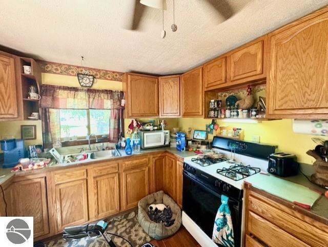 kitchen with white appliances, sink, a textured ceiling, and ceiling fan