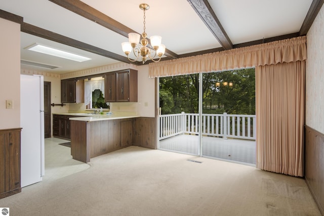 kitchen with light colored carpet, white fridge, kitchen peninsula, an inviting chandelier, and hanging light fixtures