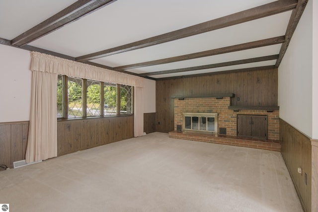 unfurnished living room with a brick fireplace, wood walls, and beamed ceiling