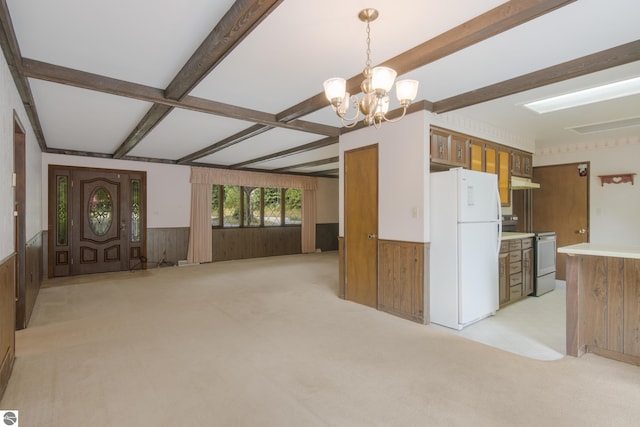 kitchen with freestanding refrigerator, beam ceiling, a wainscoted wall, and electric range