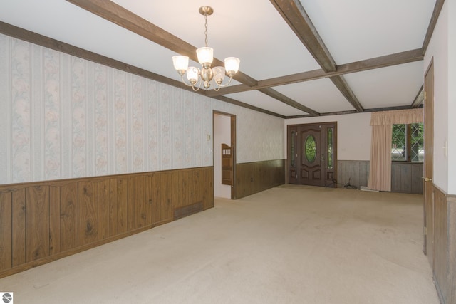 carpeted spare room featuring a wainscoted wall, wood walls, beam ceiling, wallpapered walls, and an inviting chandelier