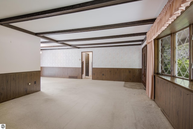 unfurnished room featuring wainscoting, beamed ceiling, wood walls, and wallpapered walls