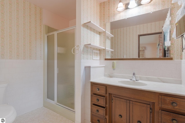 full bath featuring wallpapered walls, a shower stall, tile walls, and wainscoting