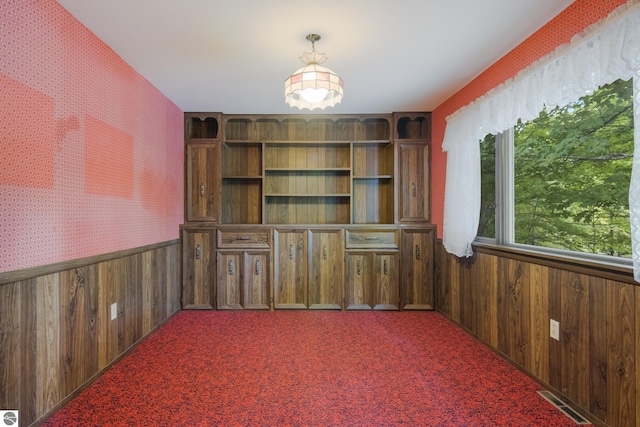 empty room featuring carpet floors, a wainscoted wall, visible vents, and wallpapered walls