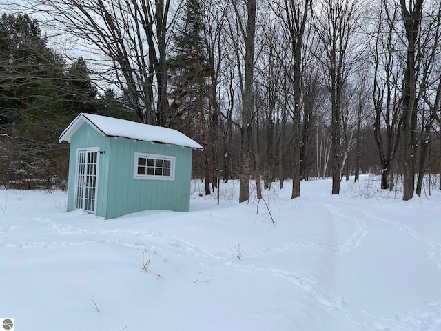 snow covered structure with an outbuilding