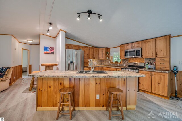 4949 N M-33, Rose City, MI 48654 - kitchen featuring light wood finished floors, a sink, stainless steel appliances, vaulted ceiling, and a kitchen bar