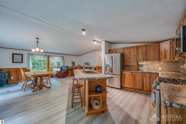 4949 N M-33, Rose City, MI 48654 - kitchen featuring a sink, appliances with stainless steel finishes, wainscoting, lofted ceiling, and a wood stove