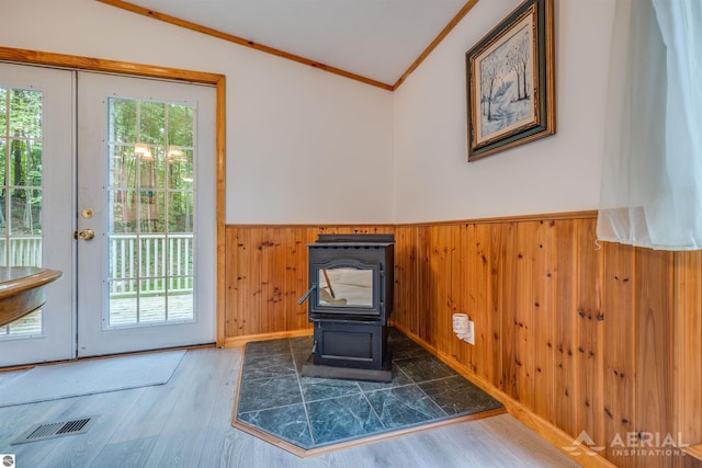 4949 N M-33, Rose City, MI 48654 - unfurnished room with visible vents, a wainscoted wall, ornamental molding, a wood stove, and wood finished floors