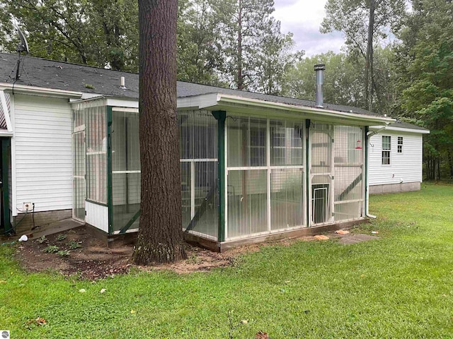 rear view of property featuring a sunroom and a yard