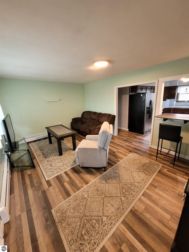 living room with a baseboard heating unit and hardwood / wood-style flooring