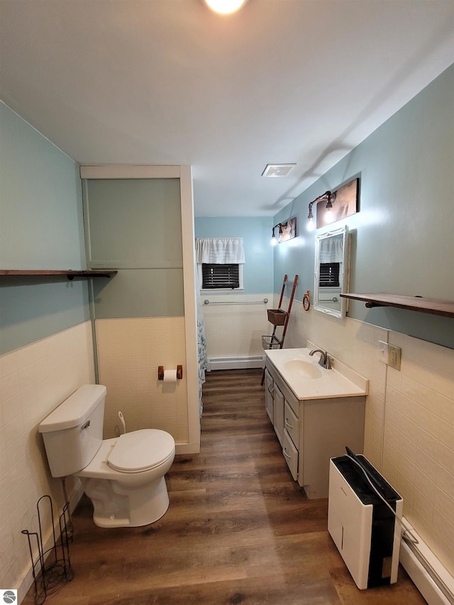 bathroom with a baseboard radiator, wood-type flooring, vanity, and tile walls