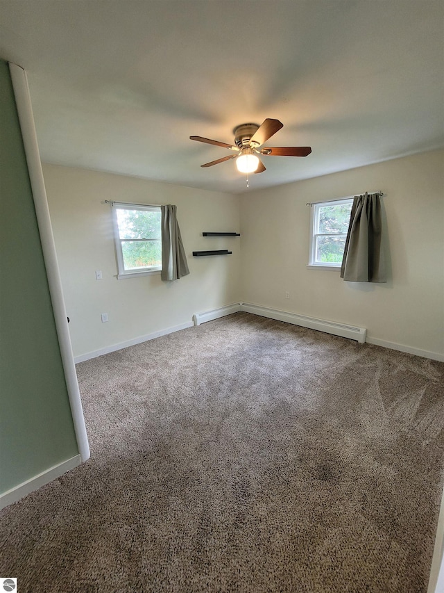 carpeted spare room featuring a baseboard heating unit, a wealth of natural light, and ceiling fan