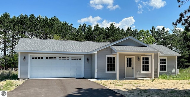 single story home featuring a garage, driveway, and roof with shingles