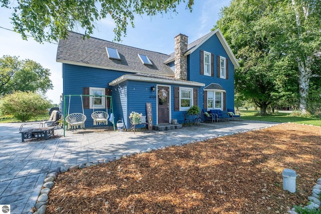 cape cod house with a patio