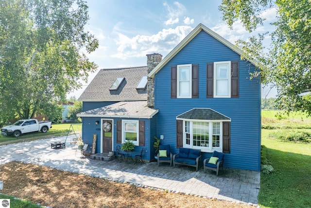 front facade featuring an outdoor hangout area, a front lawn, and a patio