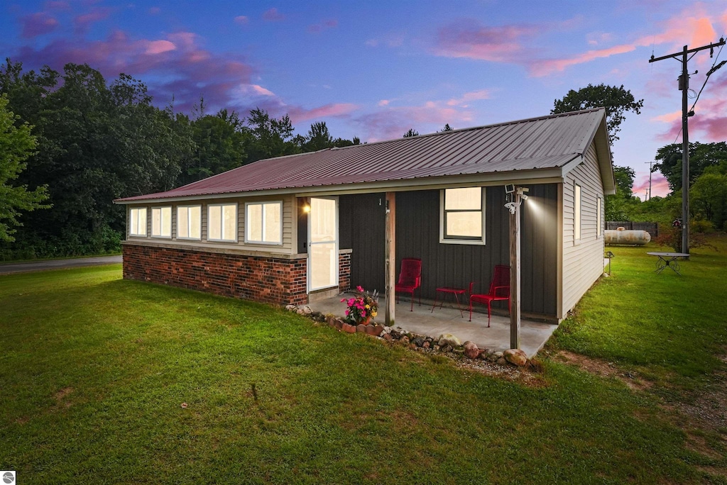 view of front of home featuring a front yard, metal roof, and a patio