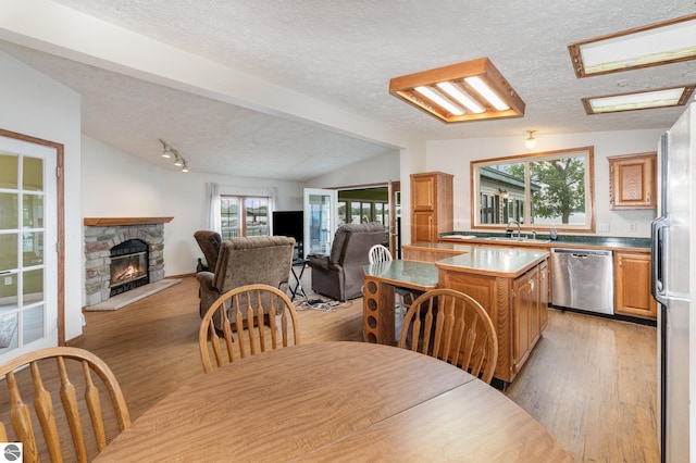 dining room with lofted ceiling, light wood-style floors, a fireplace, and a healthy amount of sunlight