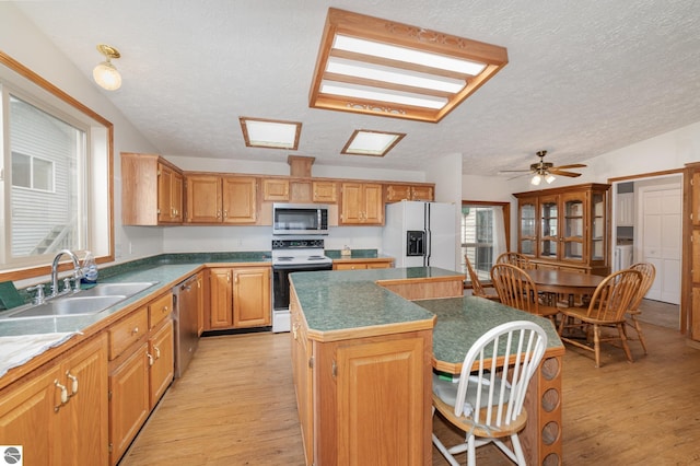 kitchen featuring light wood-style flooring, a breakfast bar area, a center island, stainless steel appliances, and a sink