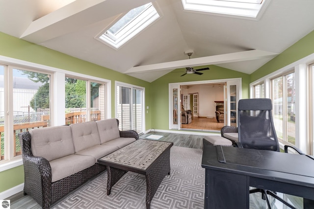 sunroom / solarium with vaulted ceiling with skylight, a wealth of natural light, and a ceiling fan