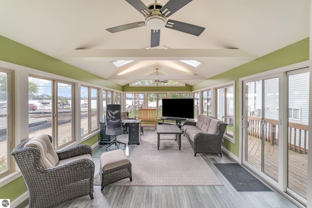 sunroom with ceiling fan, vaulted ceiling with skylight, and a healthy amount of sunlight