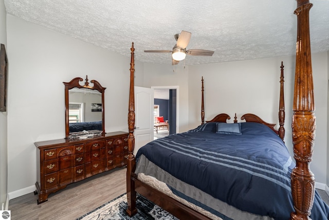 bedroom featuring light wood-style floors, a textured ceiling, baseboards, and a ceiling fan