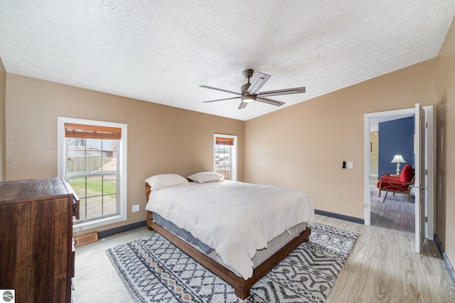 bedroom featuring ceiling fan, a textured ceiling, lofted ceiling, light wood-style flooring, and baseboards