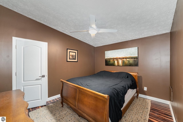 bedroom featuring baseboards, a ceiling fan, wood finished floors, vaulted ceiling, and a textured ceiling