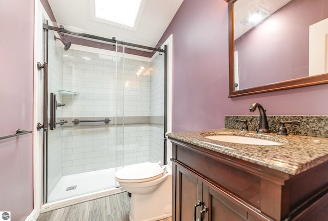 full bath featuring vanity, wood finished floors, a shower stall, and toilet