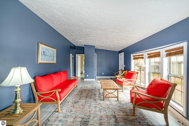 living room featuring a textured ceiling, vaulted ceiling, wood finished floors, and baseboards