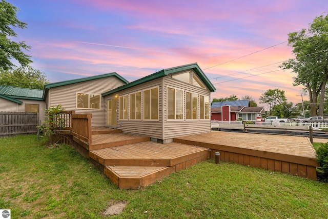 rear view of property with a yard, fence, and a wooden deck