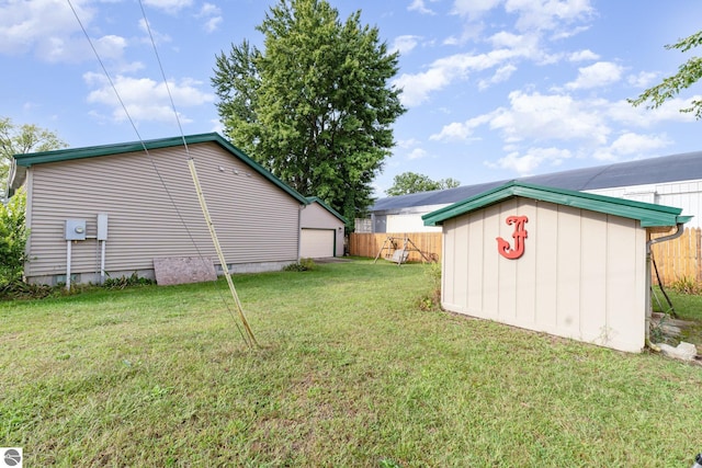 view of yard featuring a storage shed, fence, a garage, an outdoor structure, and driveway